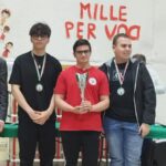 Ragazzi felici celebrano la loro vittoria al Campionato U18 di Scacchi a Barletta, con il Circolo AD Scacchi Foggia in primo piano.